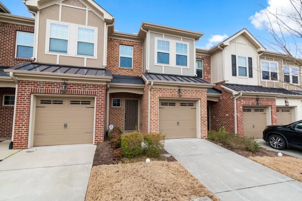 pexels-curtis-adams-1694007-7028105 A brick building with three garage doors and a driveway.